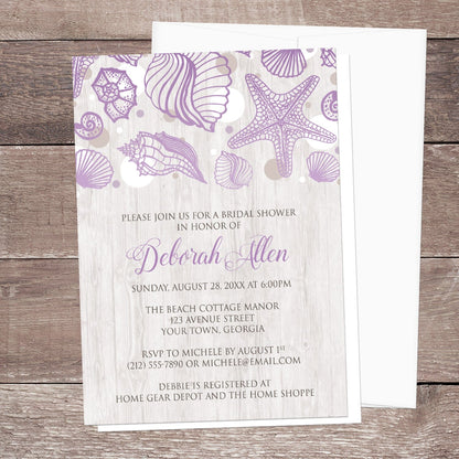 Seashell Whitewashed Wood Purple Beach Bridal Shower Invitation shown on a wooden surface with a white envelope.