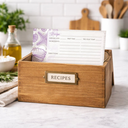 Wooden recipe box with a Seashell Whitewashed Wood Purple Beach Recipe Card on a kitchen counter