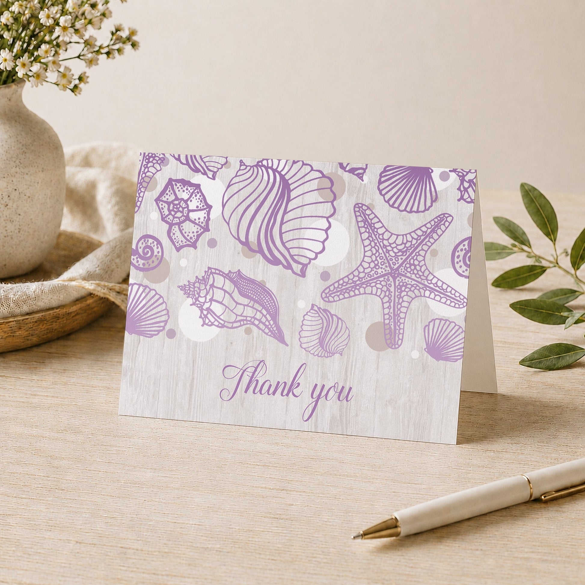 Seashell Whitewashed Wood Purple Beach Thank You Card shown on a desk with a vase, plants, and a pen.