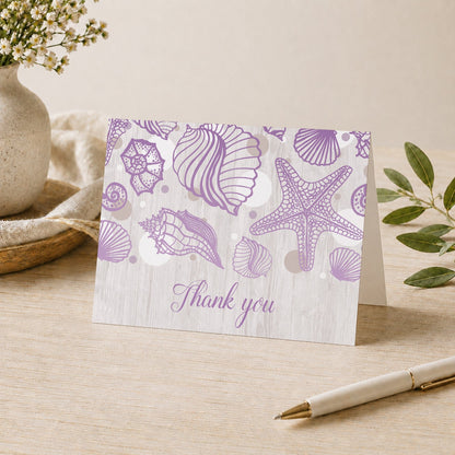 Seashell Whitewashed Wood Purple Beach Thank You Card shown on a desk with a vase, plants, and a pen.