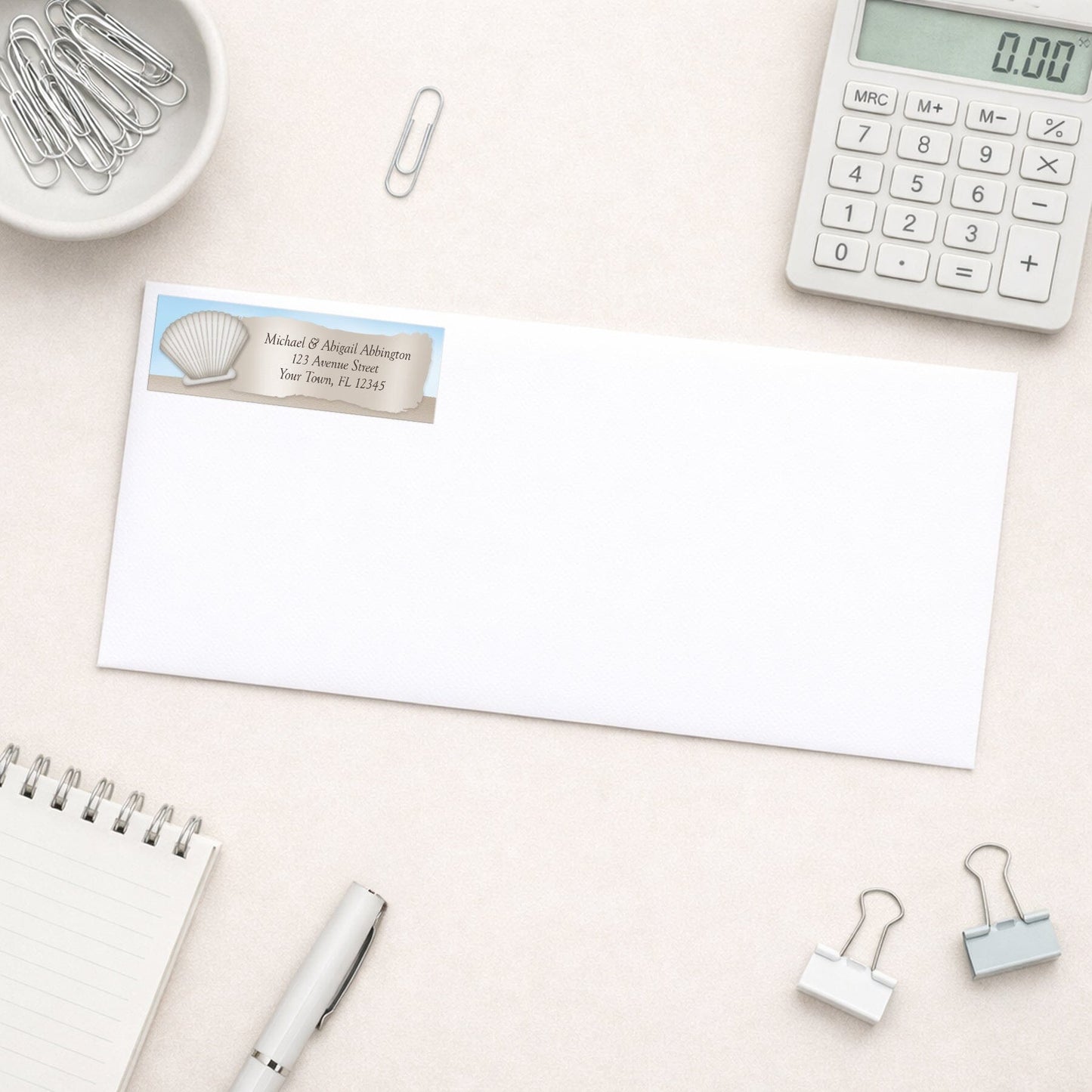 Seashell in the Sand Beach Address Label shown on a white envelope with office supplies