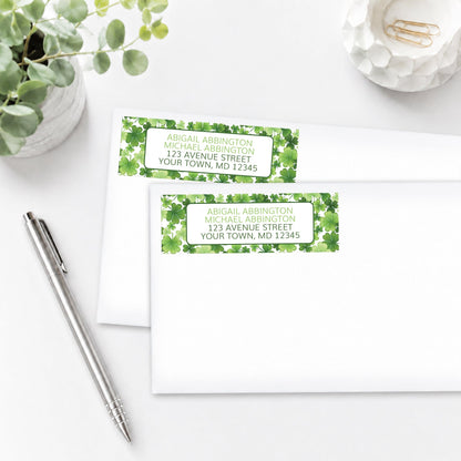 Address labels with shamrock design, shown on white envelopes, on a white surface with a pen and plant.
