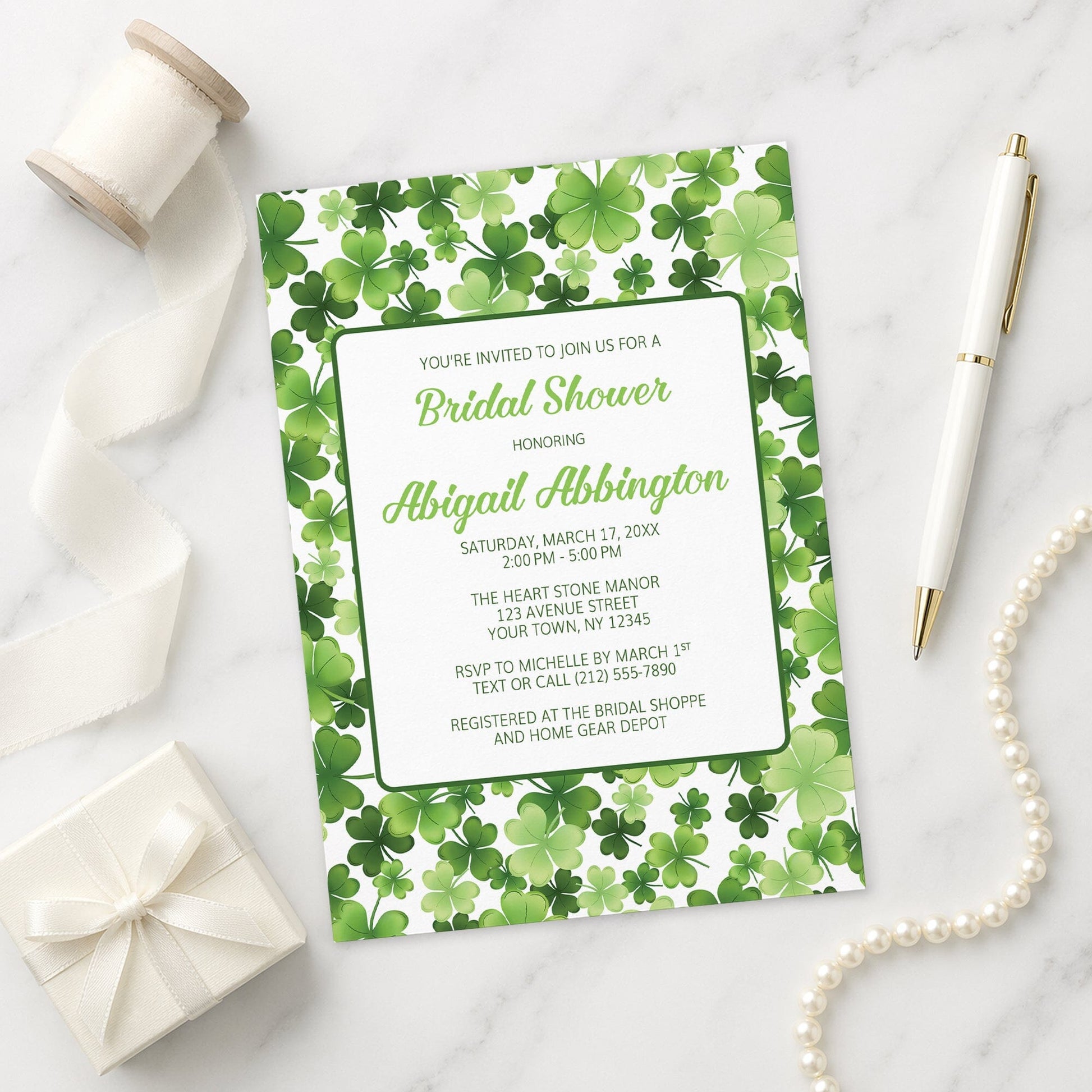 Shamrocks and 4-Leaf Clovers Bridal Shower Invitation on a marble surface with decorative items.