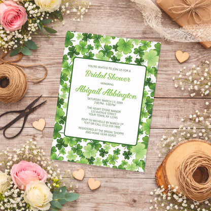 Shamrocks and 4-Leaf Clovers Bridal Shower Invitation on a wooden surface with flowers and twine.