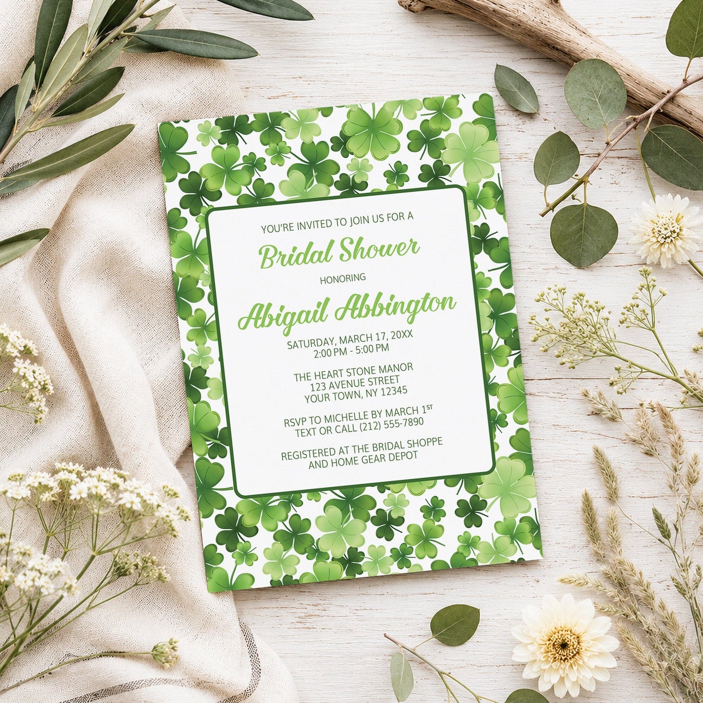 Shamrocks and 4-Leaf Clovers Bridal Shower Invitation shown on a light wooden surface with spring and summer plants.