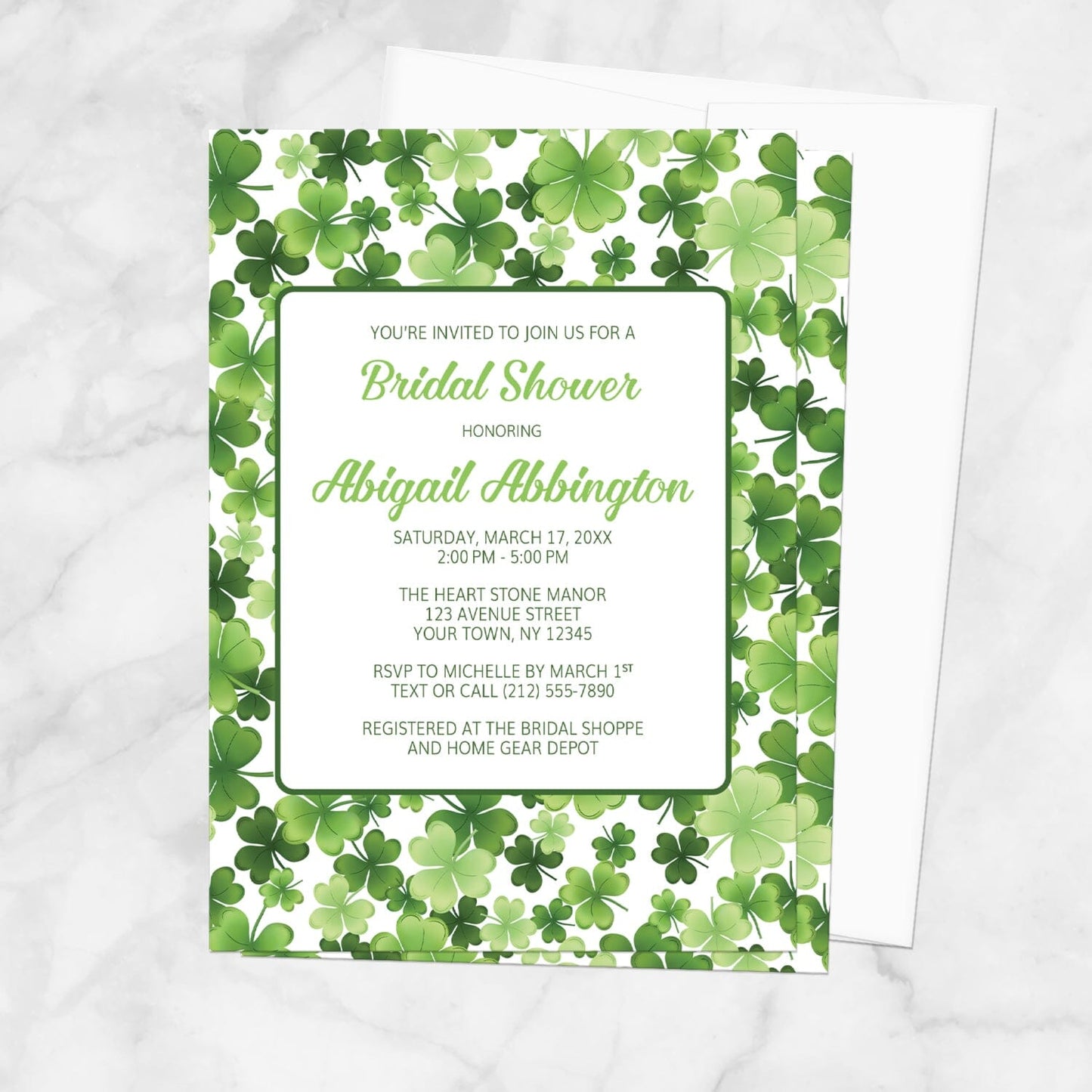 Bridal shower invitation with green shamrock pattern, displayed with a white envelope on a marble surface