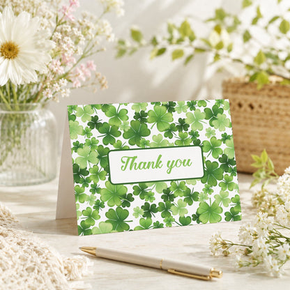 Shamrocks and 4-Leaf Clovers Thank You Card shown on a tabletop with a vase, spring and summer flowers, and a pen.