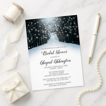 Snowy Winter Road Tree Lights Bridal Shower Invitation on a marble surface with gift box, ribbon, and pen.