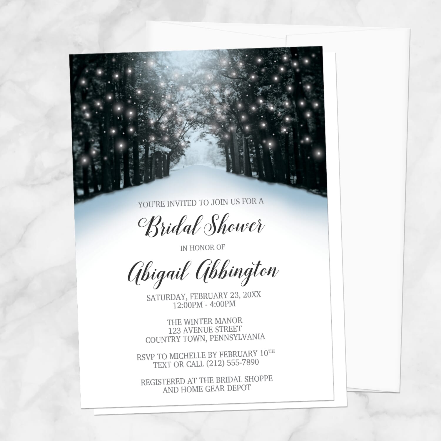 Bridal shower invitation with winter forest design, with a white envelope, laid upon on a marble surface