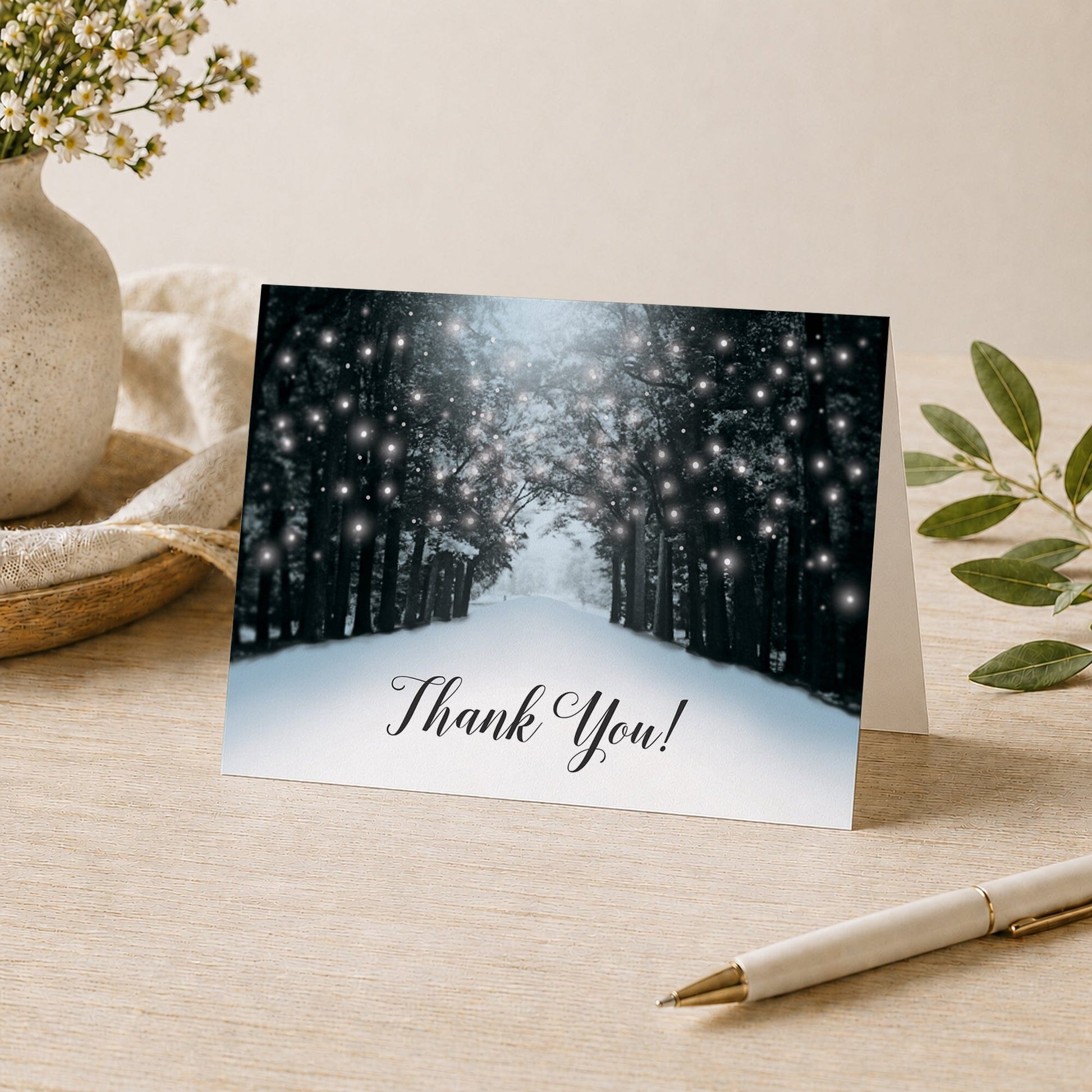 Snowy Winter Road Tree Lights Thank You Card shown on a tabletop with a pen, vase, and plants.