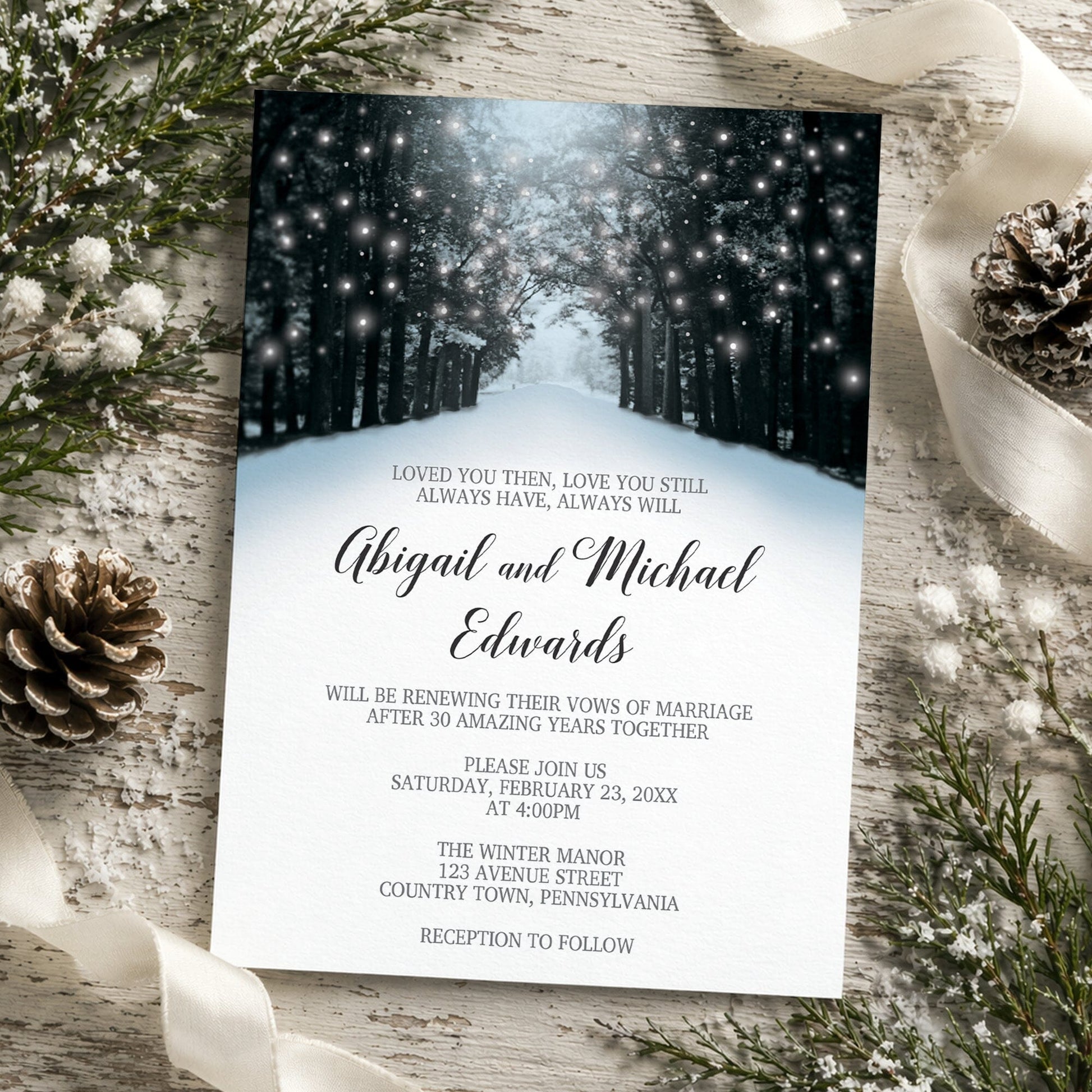 Snowy Winter Road Tree Lights Vow Renewal Invitation shown on a rustic wooden surface with winter greenery, ribbon, and pine cones.