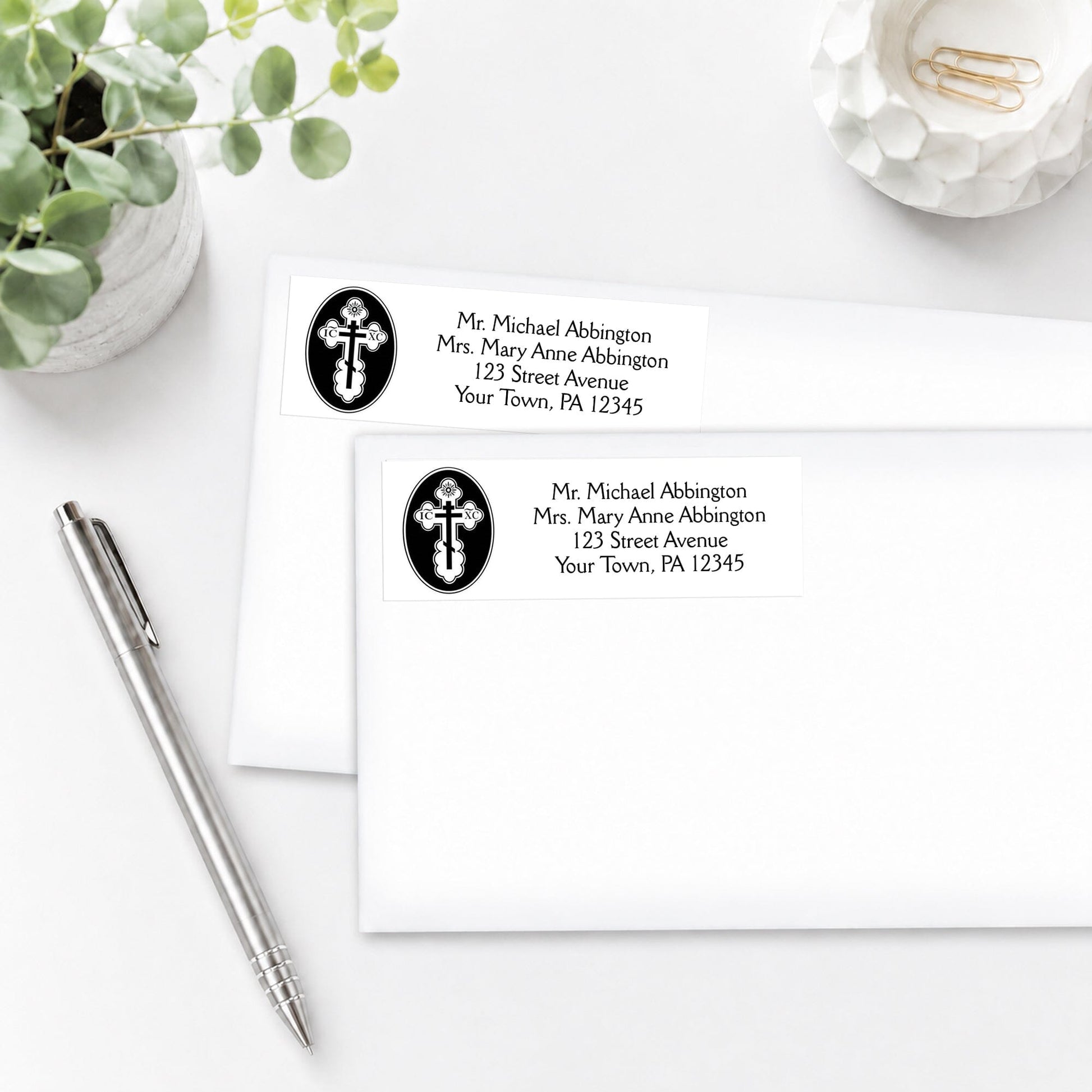 St. Olga Cross Orthodox Address Labels on white envelopes, shown on a white surface with a pen and plant.