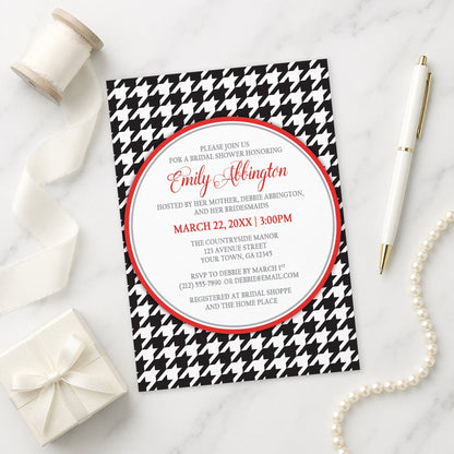 Stylish Black Houndstooth Red Bridal Shower Invitation shown on a marble surface with a white gift box, pen, ribbon, and pearls.