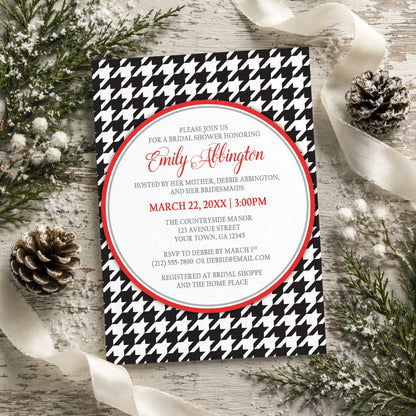 Stylish Black Houndstooth Red Bridal Shower Invitation shown on a rustic wooden surface with winter greenery, pine cones, and ribbons.