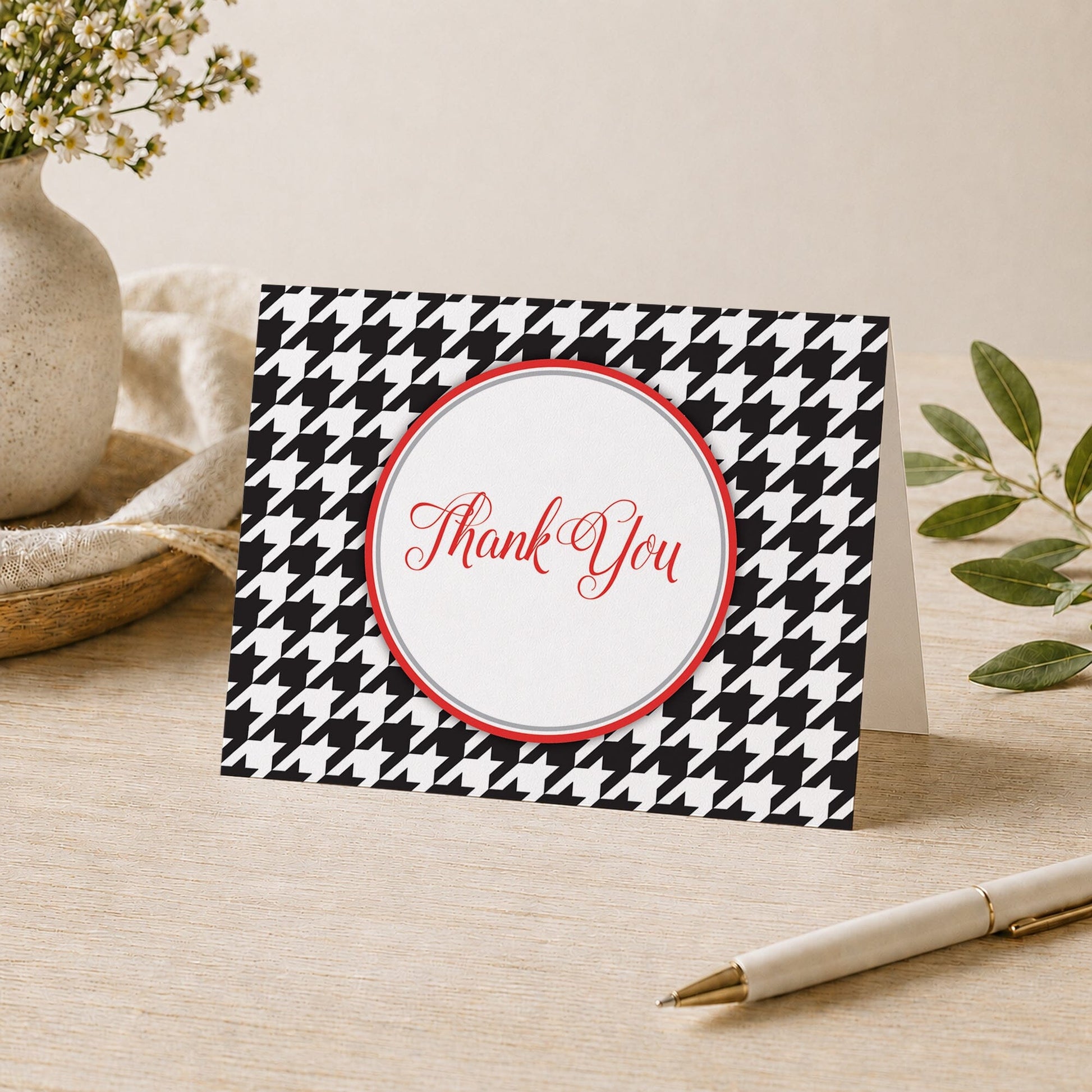 Stylish Black Houndstooth Red Thank You Card shown on a desk with a vase, plants, and a pen.