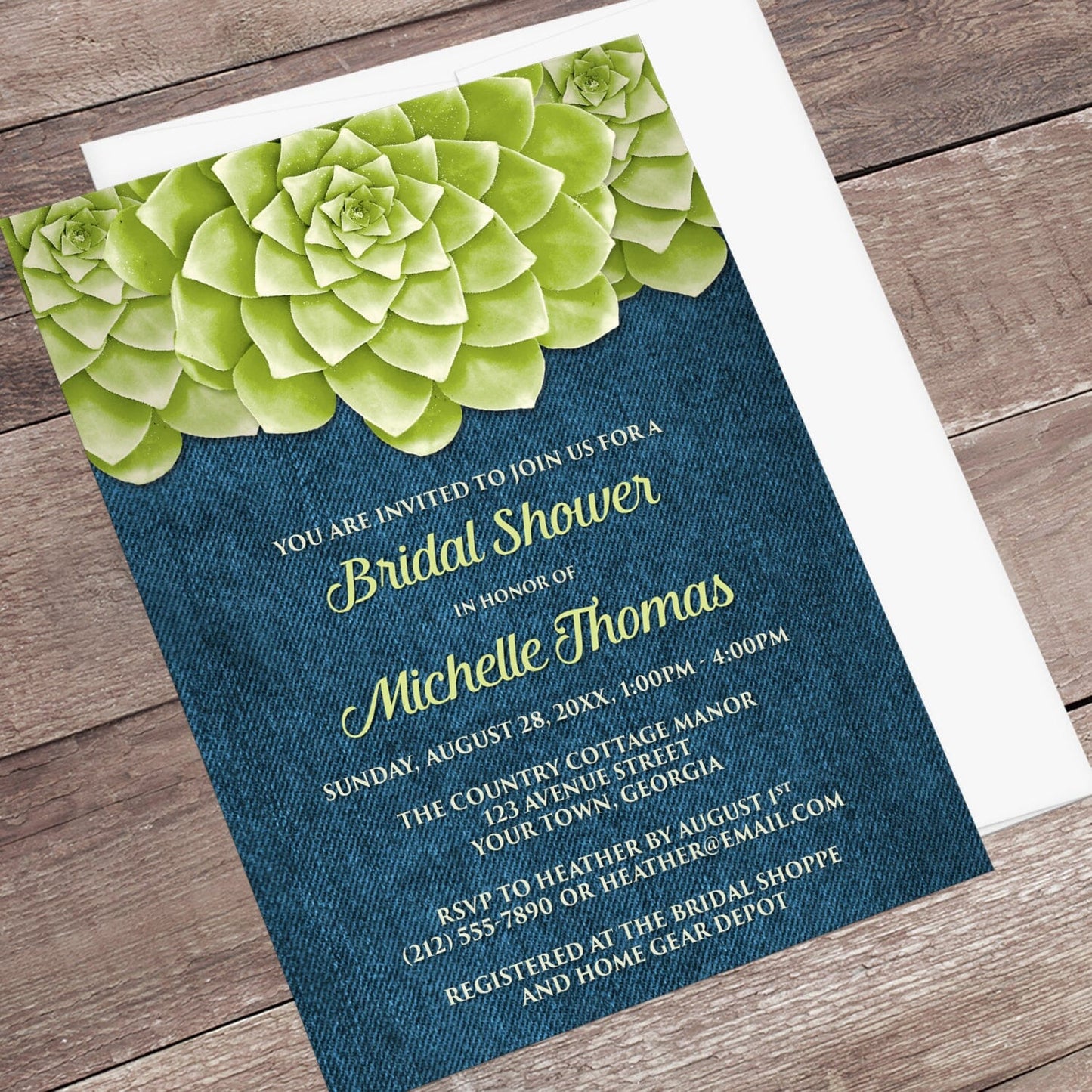 Succulent Green Blue Denim Bridal Shower Invitation shown at an angle on a wooden surface with a white envelope.