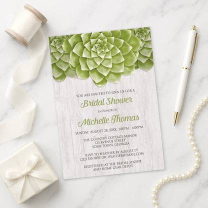 Bridal shower invitation with green succulent design shown on a marble surface with decorative items.
