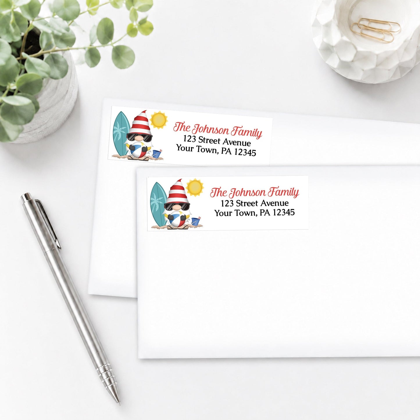 Personalized Summer Beach Gnome Address Labels, shown on white envelopes, on a white surface with a pen and plant.