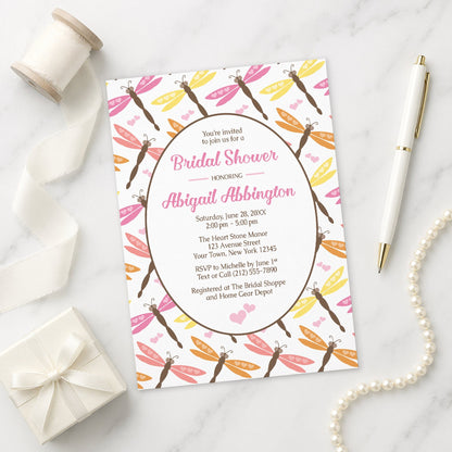 Summer Dragonfly Bridal Shower Invitation shown on a marble surface with a white gift box, pen, ribbon, and pearls.