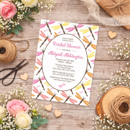 Summer Dragonfly Bridal Shower Invitation shown on a wooden surface with spring and summer flowers, small wood hearts, and twine.