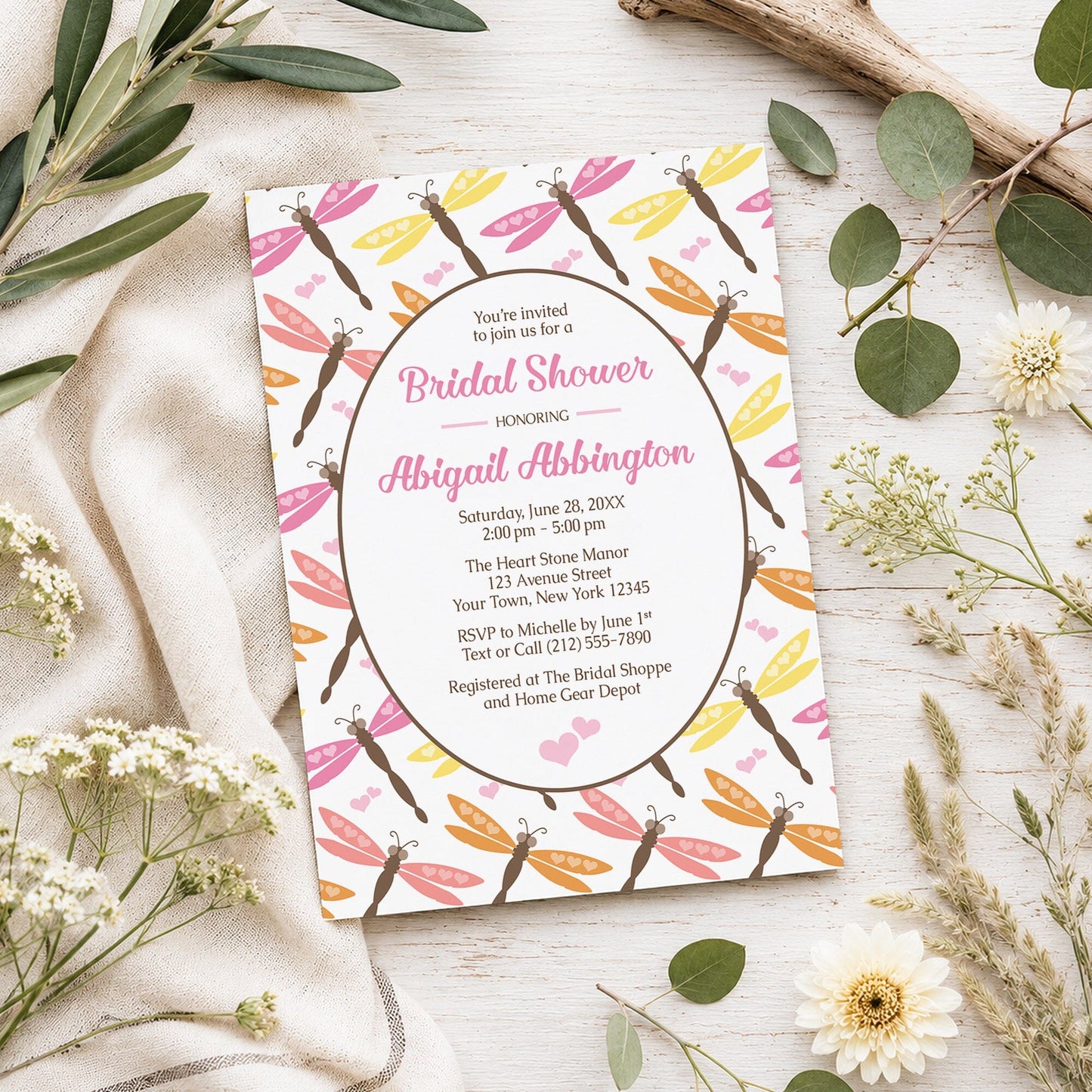Summer Dragonfly Bridal Shower Invitation shown on a light wooden surface with spring and summer plants.