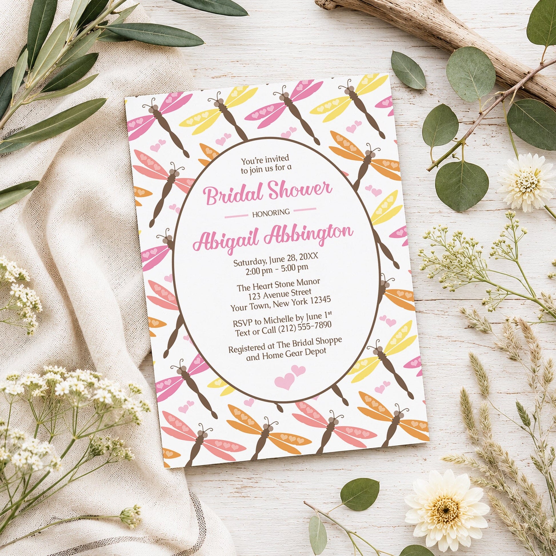 Summer Dragonfly Bridal Shower Invitation shown on a light wooden surface with spring and summer plants.