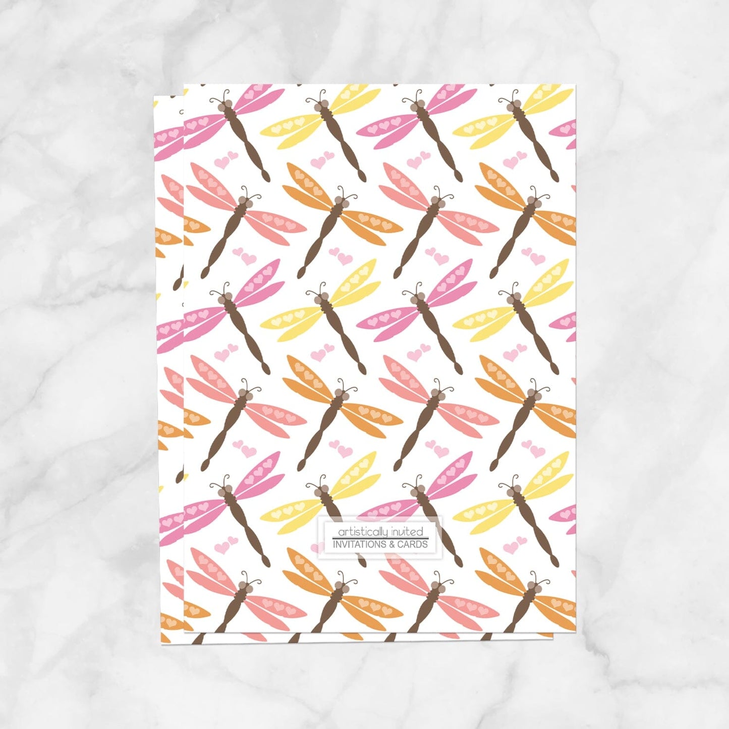 The back side of the Summer Dragonfly Bridal Shower Invitation, displaying the dragonfly pattern design and store logo, shown on a marble surface.