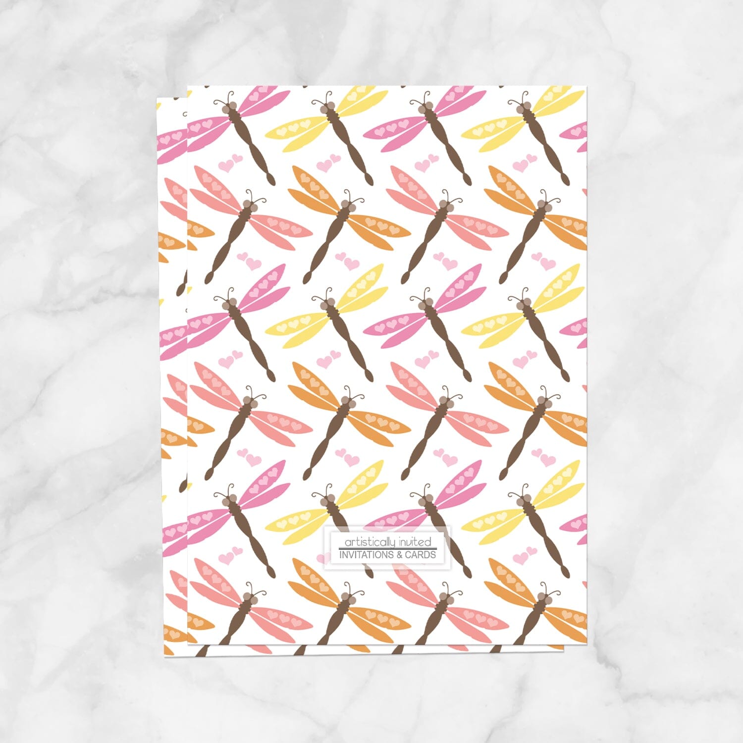 The back side of the Summer Dragonfly Bridal Shower Invitation, displaying the dragonfly pattern design and store logo, shown on a marble surface.