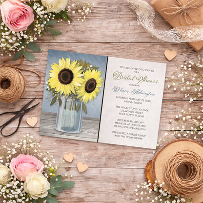 Sunflower Blue Mason Jar Rustic Bridal Shower Invitation shown on a wooden surface with summer flowers, small wood hearts, and twine.