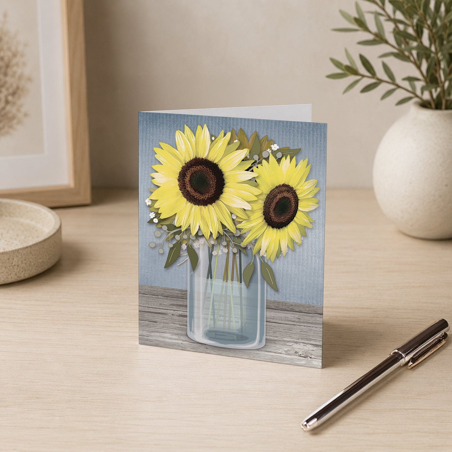 Sunflower Blue Mason Jar Rustic Note Card shown on a desk with a vase and a pen.