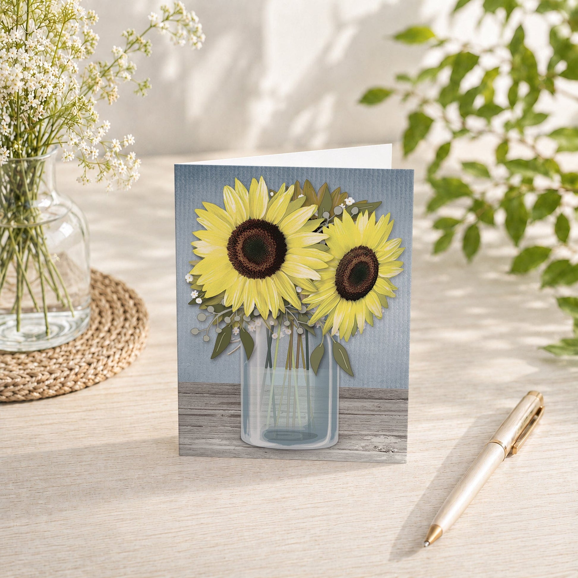 Sunflower Blue Mason Jar Rustic Note Card shown on a tabletop with a vase, spring and summer flowers, and a pen.
