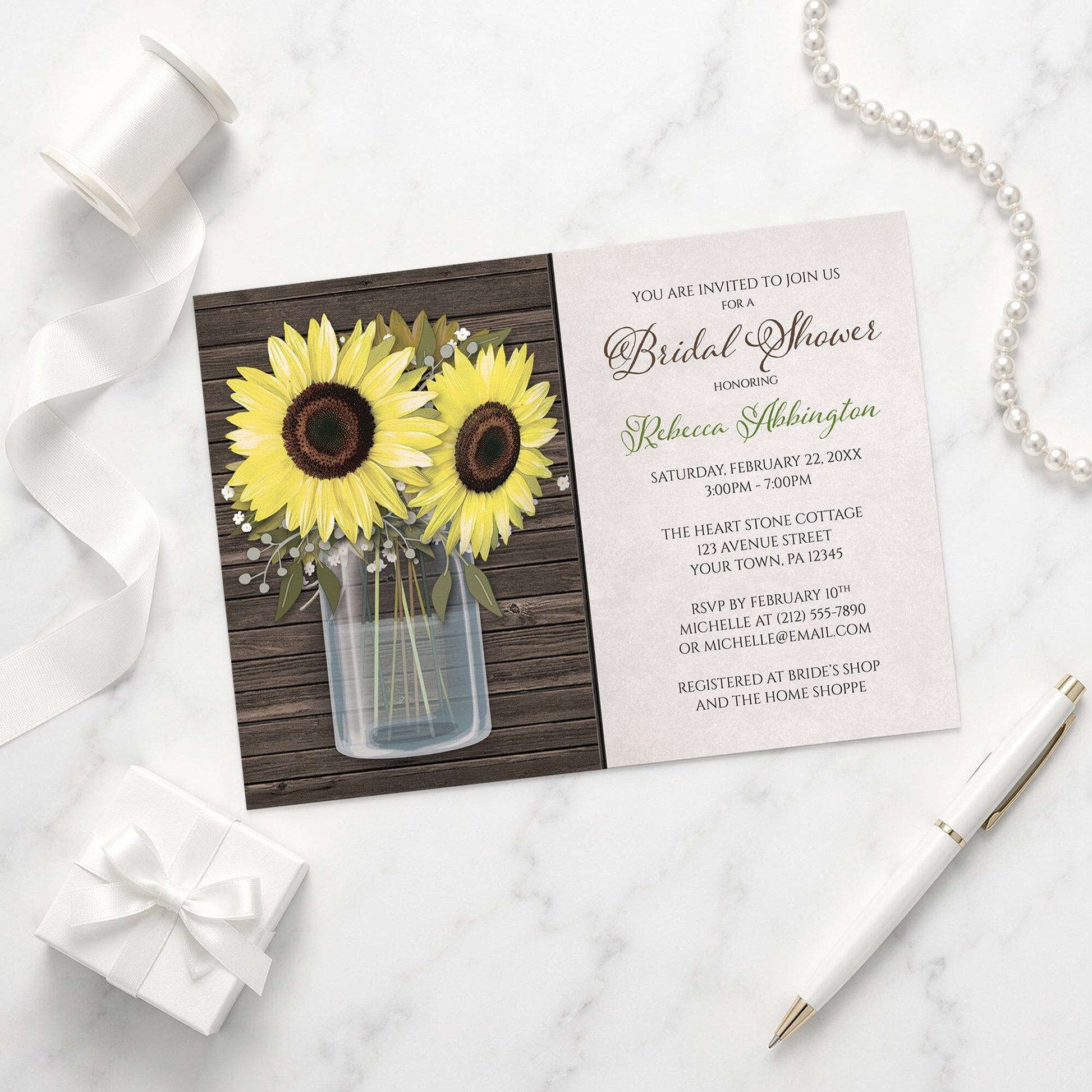Sunflower Wood Mason Jar Rustic Bridal Shower Invitation shown on a marble surface with a white gift box, pen, ribbon, and pearls.
