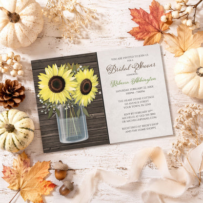 Sunflower Wood Mason Jar Rustic Bridal Shower Invitation shown on a painted wooden surface with fall leaves and autumn decor.