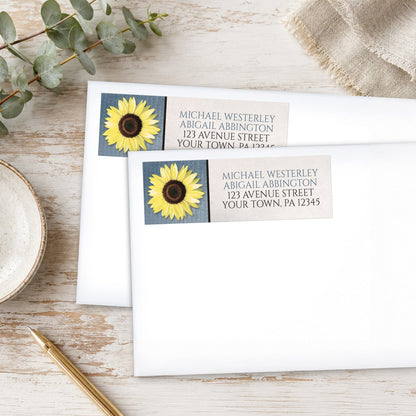 Sunflower and Blue Rustic Address Labels, shown on white envelopes, on a wooden surface with eucalyptus leaves and a pen.