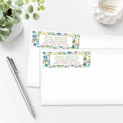 Sunny Summer Flowers Address Labels shown on white envelopes, on a white surface with a plant and a pen.