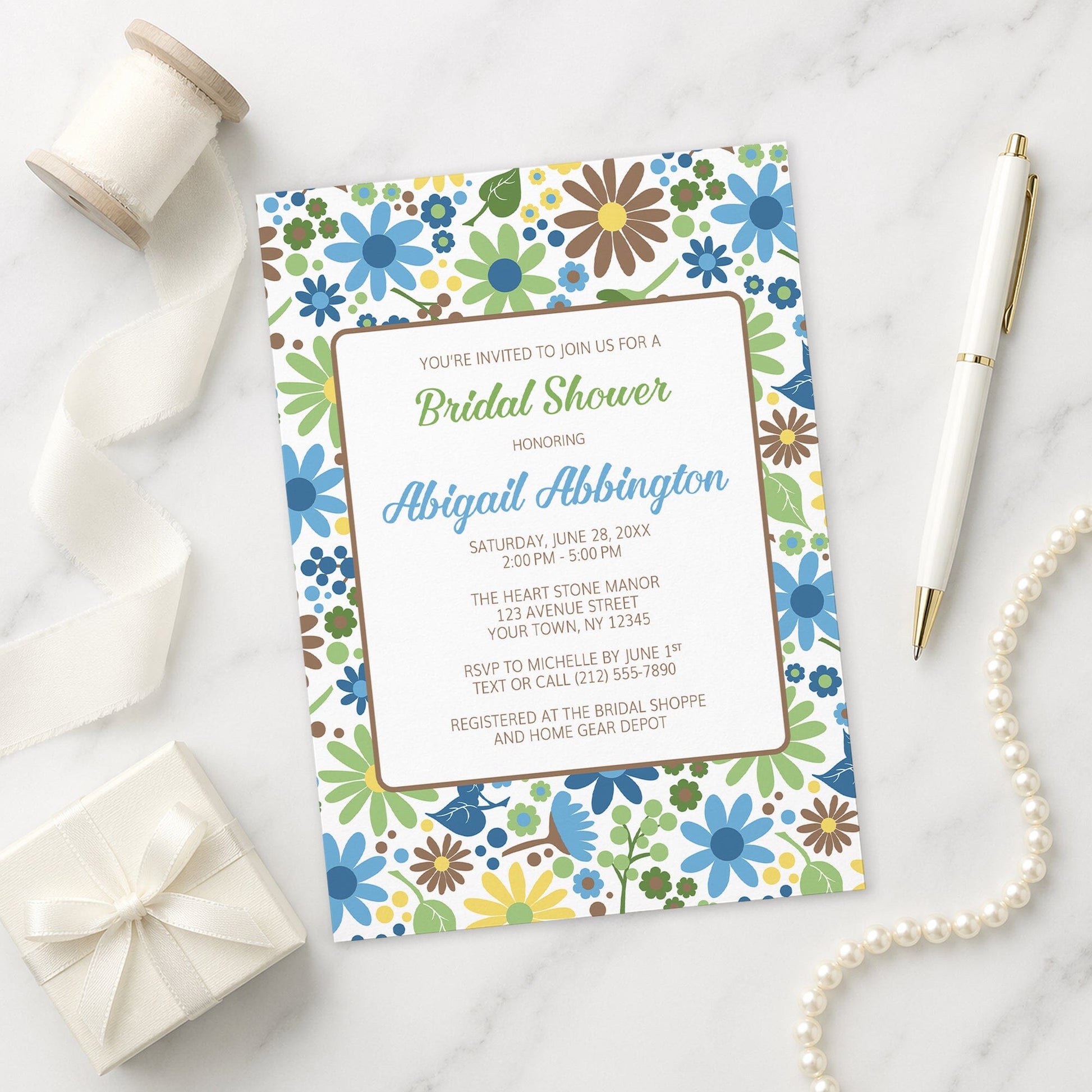 Sunny Summer Flowers Bridal Shower Invitation on a marble surface with decorative items.