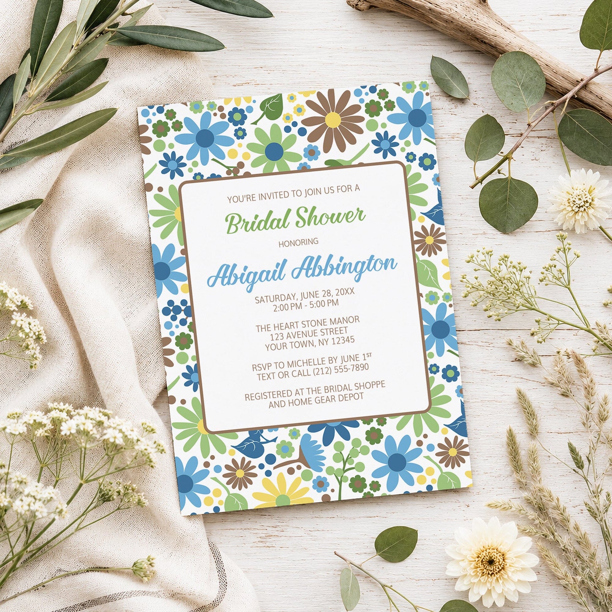 Sunny Summer Flowers Bridal Shower Invitation shown on a light wooden surface with spring and summer plants.