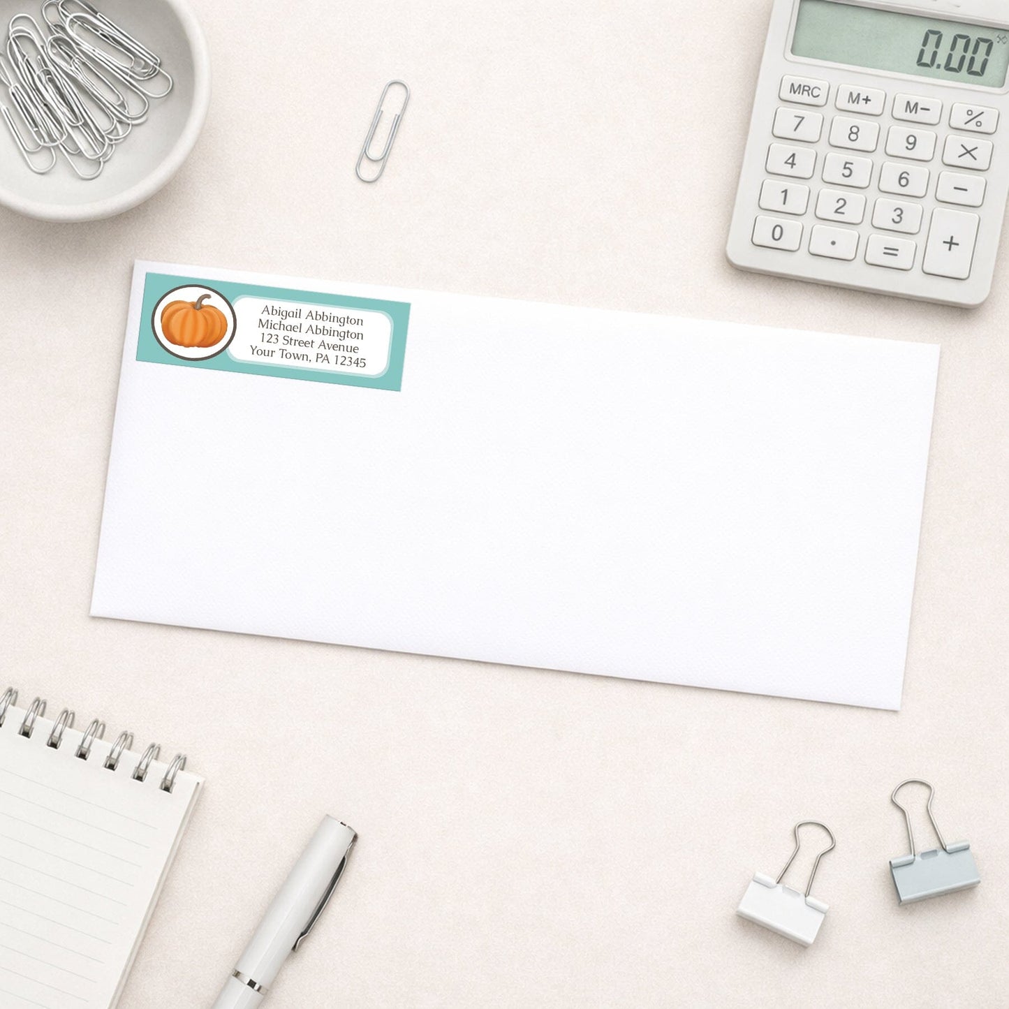Teal Pumpkin Address Label shown on a white envelope with everyday office supplies