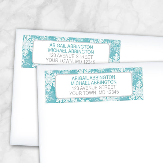 2 Teal Snowflake Winter Return Address Labels shown on white envelopes on a marble surface