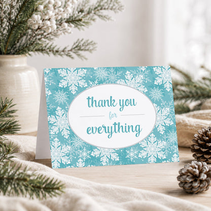 Teal Snowflake Winter Thank You Card shown on a tabletop with a vase, winter greenery, and pine cones.