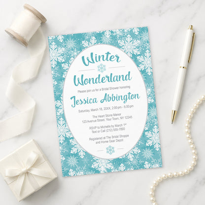 Teal Snowflake Winter Wonderland Bridal Shower Invitation shown on a marble surface with a white gift box, pen, ribbon, and pearls.