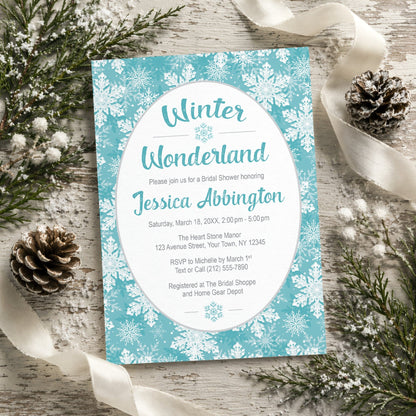 Teal Snowflake Winter Wonderland Bridal Shower Invitation shown on a rustic wooden surface with winter greenery, pine cones, and ribbon.