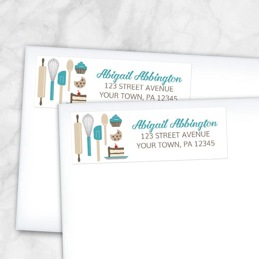 Turquoise Baking Address Labels at Artistically Invited. Image shows 2 labels on envelopes. High-quality address labels designed with cute kitchen baking tools and baked treats in turquoise, brown, gray, and beige on the left side over a white background. Your personalized return address is custom printed in turquoise and brown to the right of the turquoise baking tools and baked goods design. These premium return address labels are great for bakers, pastry chefs, or anyone who loves baking.