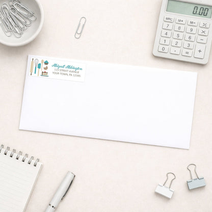 Turquoise Baking Address Label shown on a white envelope with everyday office supplies