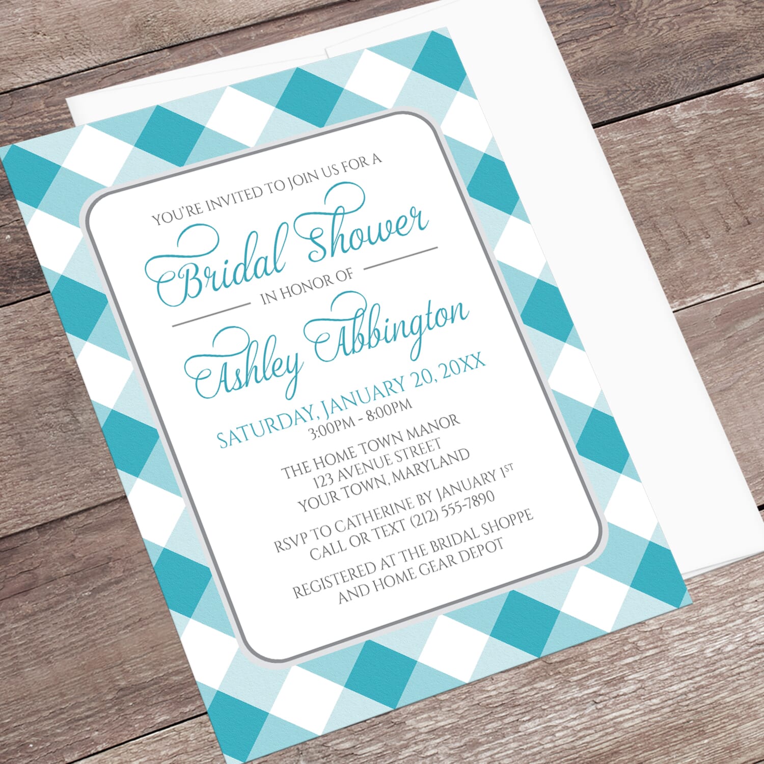 Bridal shower invitation with turquoise and white checkered border, displayed at an angle with a white envelope on a wooden surface