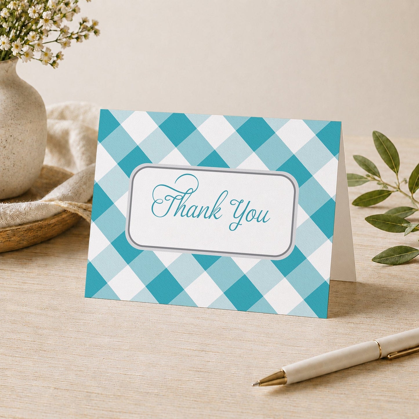 Turquoise Gingham Thank You Card shown on a desk with a vase, plants, and a pen.