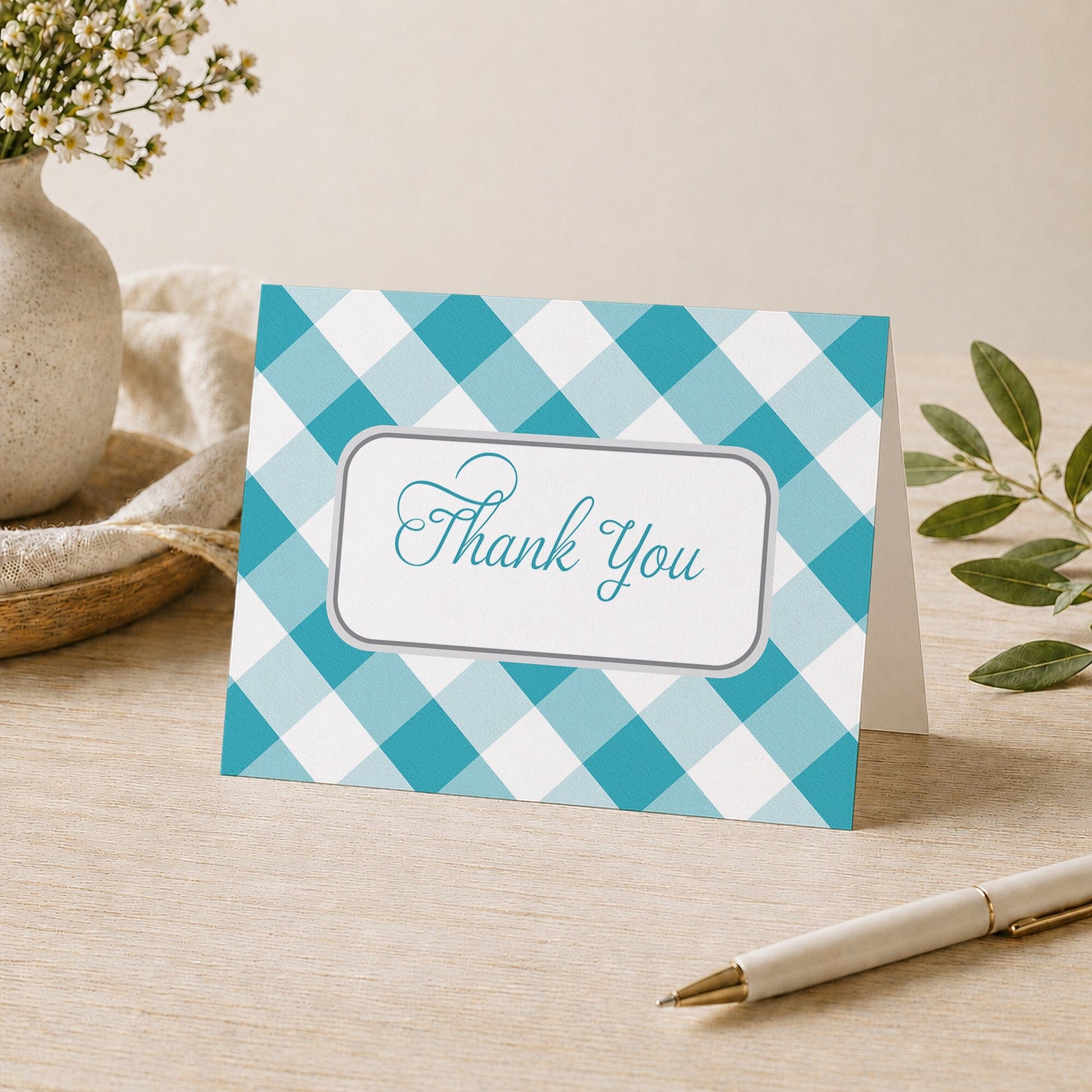 Turquoise Gingham Thank You Card shown on a desk with a vase, plants, and a pen.