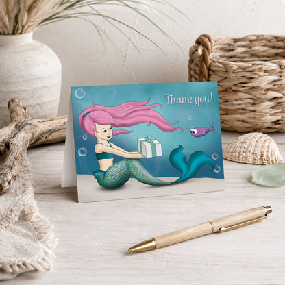 Under the Sea Mermaid Thank You Card shown on a beach house tabletop with coastal decor and a pen.