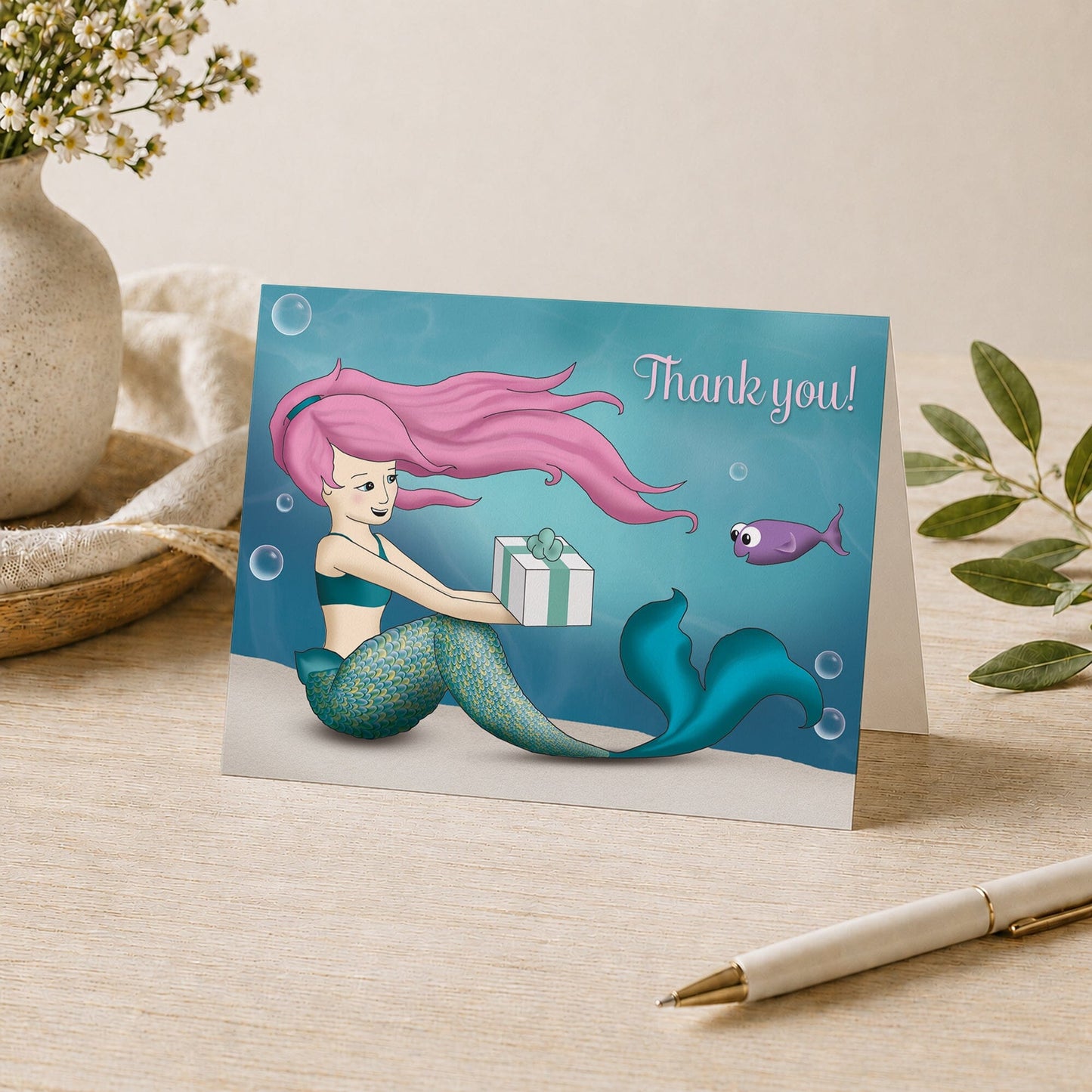 Under the Sea Mermaid Thank You Card shown on a desk with a vase, plants, and a pen.