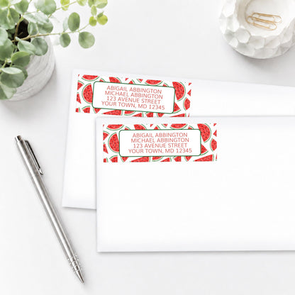 Watermelon Slices Address Labels with watermelon pattern, shown on white envelopes, on a white surface with a pen and plant.